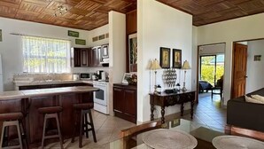 A kitchen with a bar area, wooden ceiling, and a dining table with placemats. - Top View Cottage in Lake Arenal (Río Chiquito)