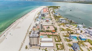Oversigtsbillede af et kysthotel med strand, flere bygninger og en lystbådehavn.