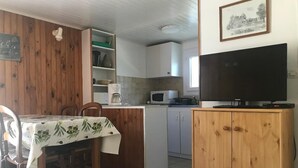 Keittiössä on ruokapöytä, tuoleja, mikroaaltouuni, kaappeja ja televisio.