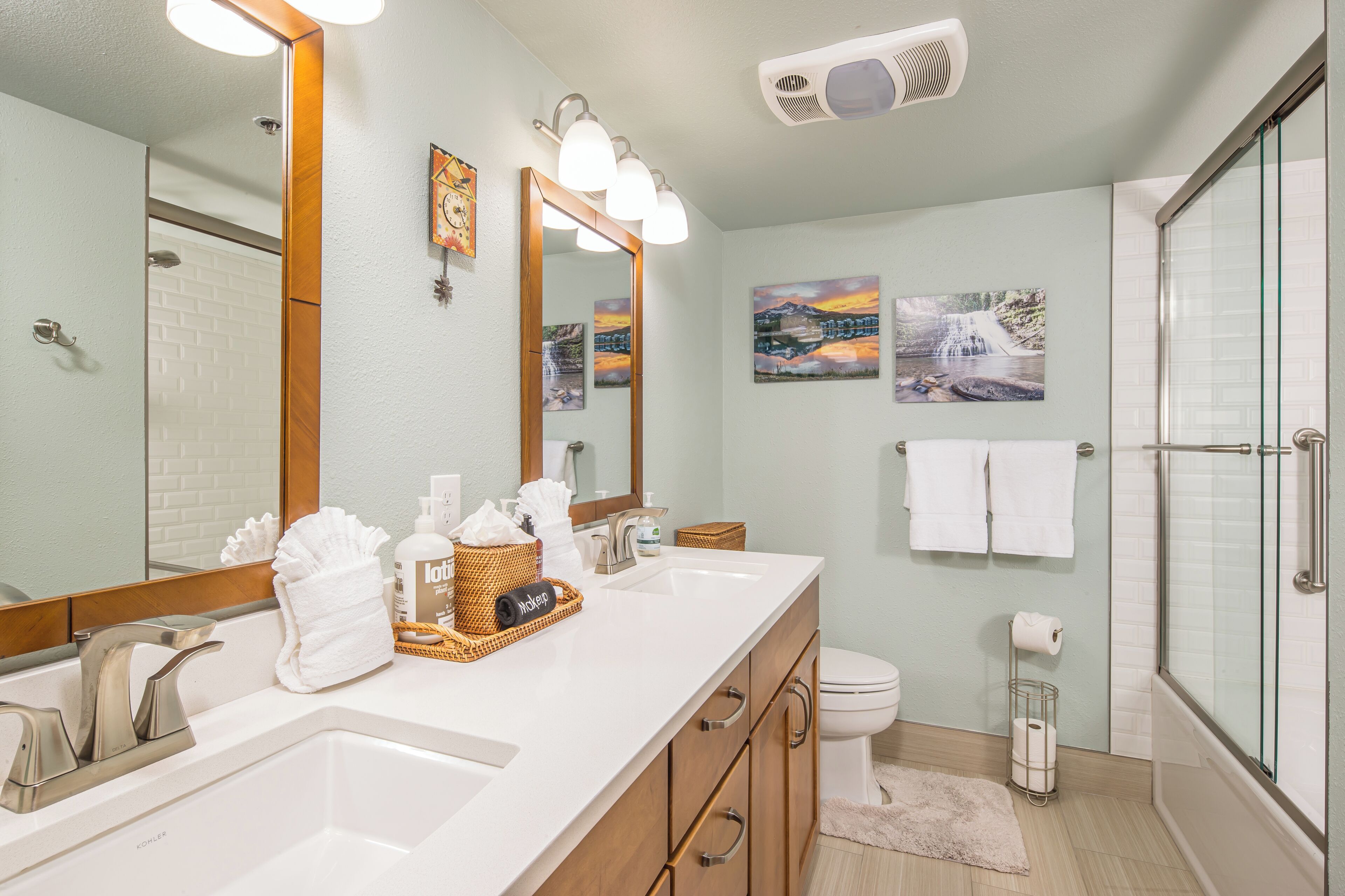 A bathroom with a white sink, a large mirror, a shower, and a toilet.