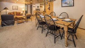 A dining area with a wooden table, black chairs, and a chandelier. - NEW! Ski. Hike. Fish. Big Sky Mountain Village (Big Sky)