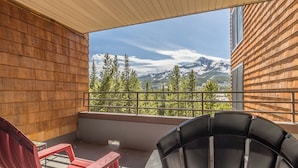A balcony with two chairs, a view of mountains, and a wooden exterior wall. - NEW! Ski. Hike. Fish. Big Sky Mountain Village (Big Sky)