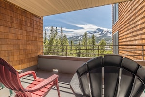 A balcony with two chairs, a view of mountains, and a wooden exterior wall. - NEW! Ski. Hike. Fish. Big Sky Mountain Village (Big Sky)