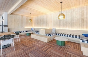 A modern interior with wooden panel walls, a wooden floor, and a seating area with a sofa and chairs.