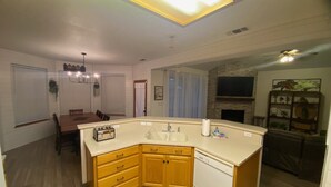 Una cocina moderna con lavavajillas integrado, armarios de madera y un comedor con mesa y sillas.