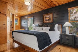 Ein Schlafzimmer mit Holzwänden, einem Bett, Nachttischlampen und einem gerahmten Bild an der Wand.