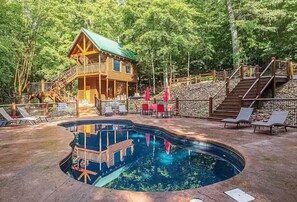 Eine Holzhütte mit Schwimmbad, umgeben von Bäumen.