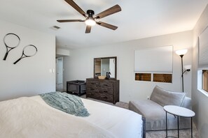 Une chambre à coucher avec un lit, une commode, un miroir et un ventilateur de plafond.