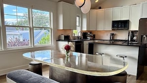 Une cuisine moderne dotée d’un îlot central, de luminaires suspendus et de grandes fenêtres.