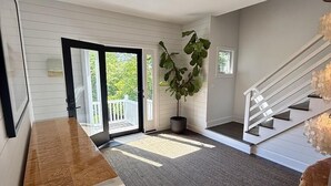 Un hall d’entrée spacieux, agrémenté d’un banc en bois, d’une plante en pot et d’un escalier menant à l’étage supérieur.