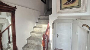 A staircase with a patterned carpet, a wooden handrail, and a reception area with a door. - Nisa Pansiyon (Ayvalık)