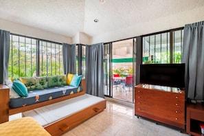 A room with a sofa, a TV, and a sliding glass door leading to an outdoor area.