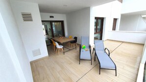 Een kamer met houten vloer, een eettafel met stoelen, een bank en een raam.