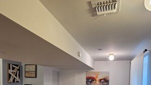 Uma sala de estar com televisão, duas cadeiras, um armário de madeira escura e obras de arte nas paredes.