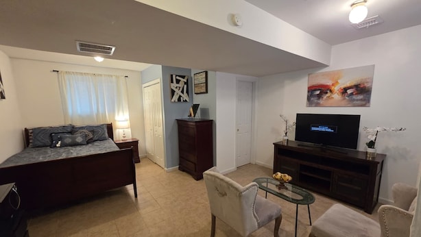 Uma sala de estar com uma cama, uma televisão, uma mesa de centro e um sofá.