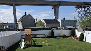 Um quintal com área de recreação, um pátio de tijolos e vista para uma ponte e edifícios.