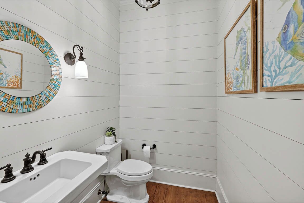 A bathroom with a white sink, toilet, and a mirror with a mosaic frame.