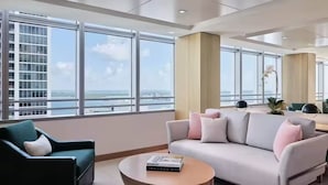 Un hall moderno de hotel con ventanas amplias, un sofá, una silla y una mesita de café.
