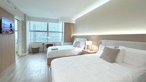 Habitación de hotel con dos camas, un escritorio, una silla, un televisor y una ventana con persianas.