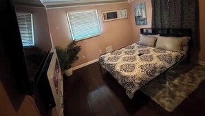 A bedroom with a bed, a potted plant, a window, and a painting on the wall. -     Relax & Unwind Stylish Decatur Home Near Downtown ATL (Decatur)