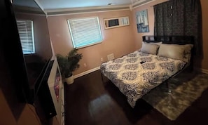 A bedroom with a bed, a potted plant, a window, and a painting on the wall. -     Relax & Unwind Stylish Decatur Home Near Downtown ATL (Decatur)