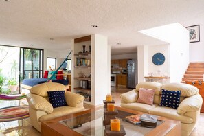 Ein geräumiges Wohnzimmer mit Ledersofas, einem Glastisch sowie Blick auf die Küche und den Essbereich.