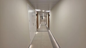 A long, narrow hotel corridor with doors on both sides and a tiled floor. - Dream retreat pool and gym (Gibraltar)