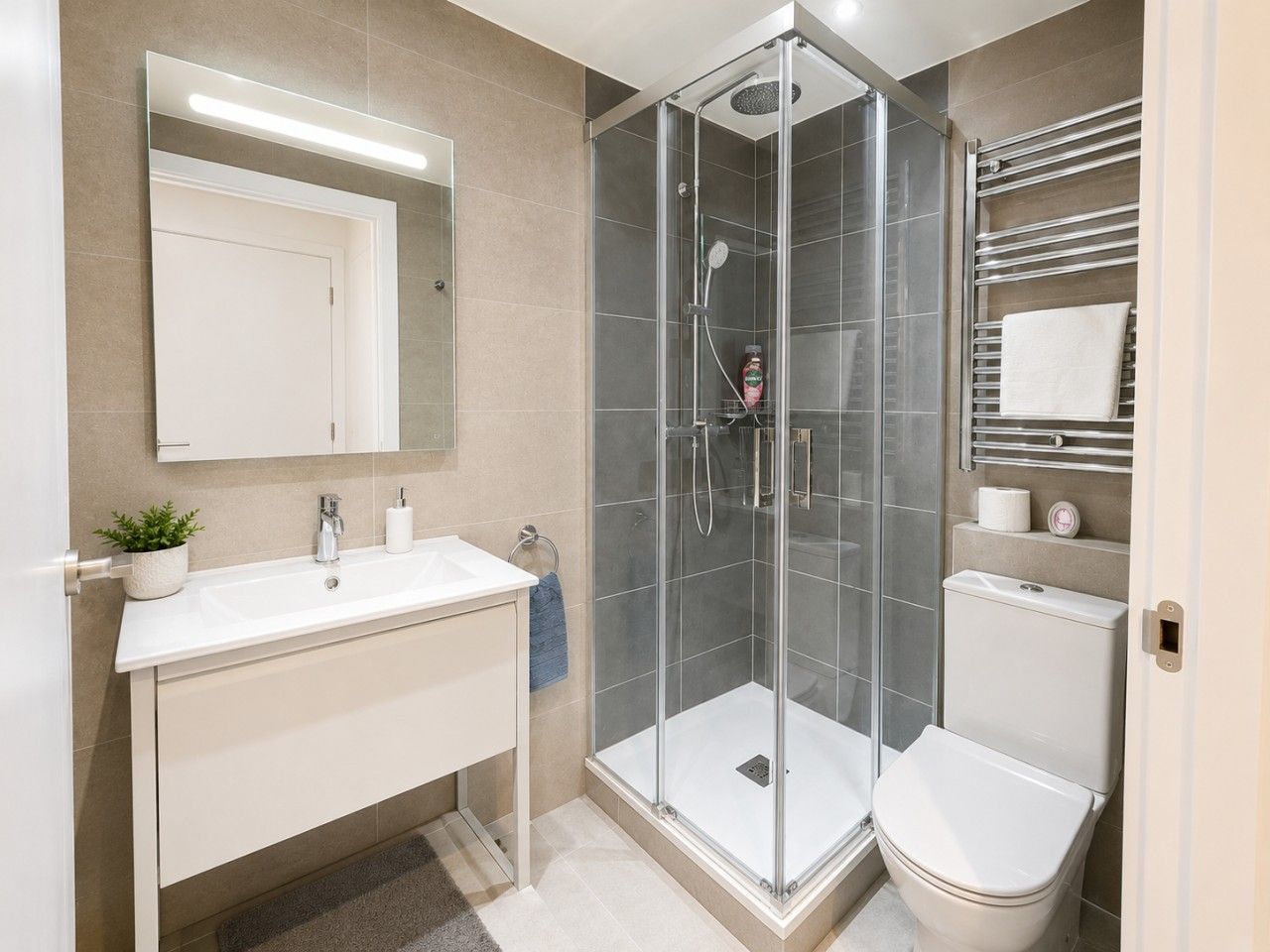 Een moderne badkamer met een douchecabine van glas, een witte wastafel en een toilet.