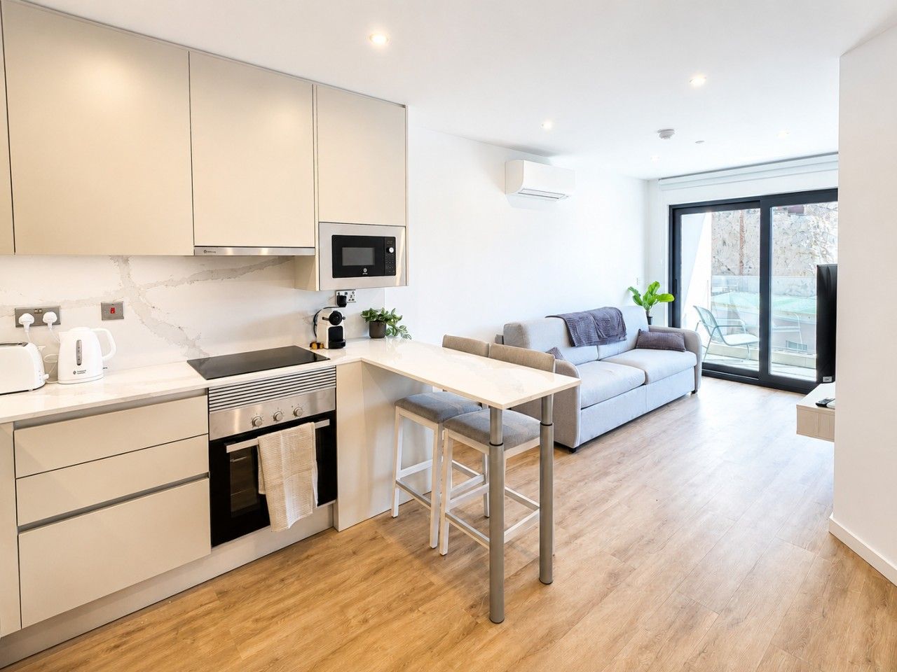 Een moderne keuken met een eethoek, een ingebouwde oven en een groot raam.