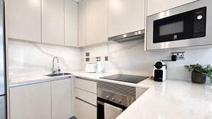 A modern kitchen with white cabinets, a stainless steel microwave, and a built-in oven. - Dream retreat pool and gym (Gibraltar)