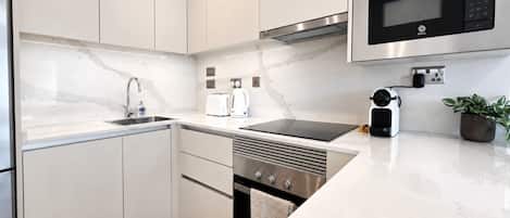 A modern kitchen with white cabinets, a stainless steel microwave, and a built-in oven.