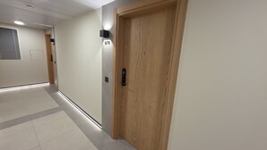 A hallway with a wooden door, a wall-mounted light, and a doorbell. - Dream retreat pool and gym (Gibraltar)