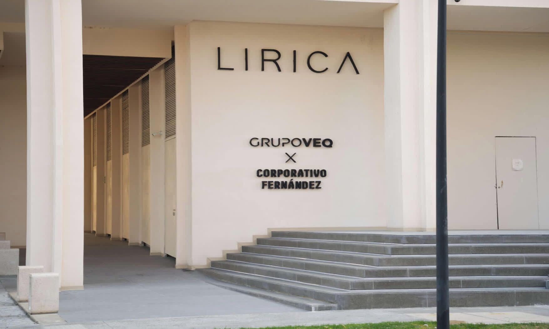 A building entrance with a staircase leading up to a door. The wall has a sign that reads 'LIRICA GRUPOVEQ CORPORATIVO FERNÁNDEZ'.
