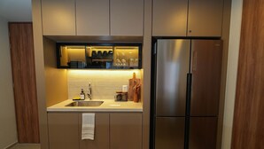 A modern kitchen with a stainless steel refrigerator, a built-in oven, and a countertop with a sink and storage cabinets.