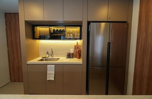 Eine moderne Küche mit einem Edelstahl-Kühlschrank, einem eingebauten Backofen und einer Arbeitsplatte mit Spüle und Stauraumschränken.