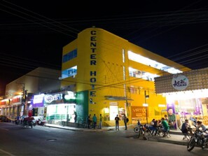 Un edificio amarillo con letrero que dice 'CENTER HOTEL', un escaparate visible y una zona de estacionamiento para bicicletas.