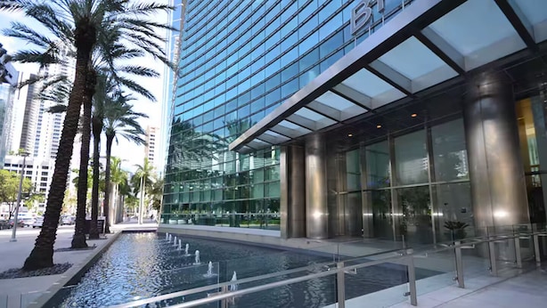 A modern building with a glass facade, a water feature, and palm trees. - ★ EXCLUSIVE Luxury Studio with FREE Parking ★ (Miami)