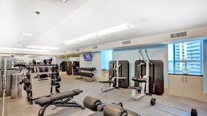 A gym with various exercise equipment, a television, and a window with a view of buildings. - ★ EXCLUSIVE Luxury Studio with FREE Parking ★ (Miami)