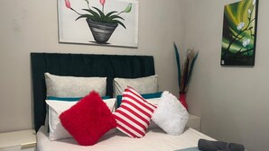 Un lit bien fait, avec des oreillers et une couverture, une table de chevet et deux tableaux accrochés au mur.