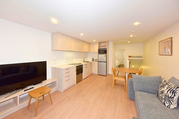 A compact living space with a kitchenette, a dining area, and a seating area with a TV and a sofa.