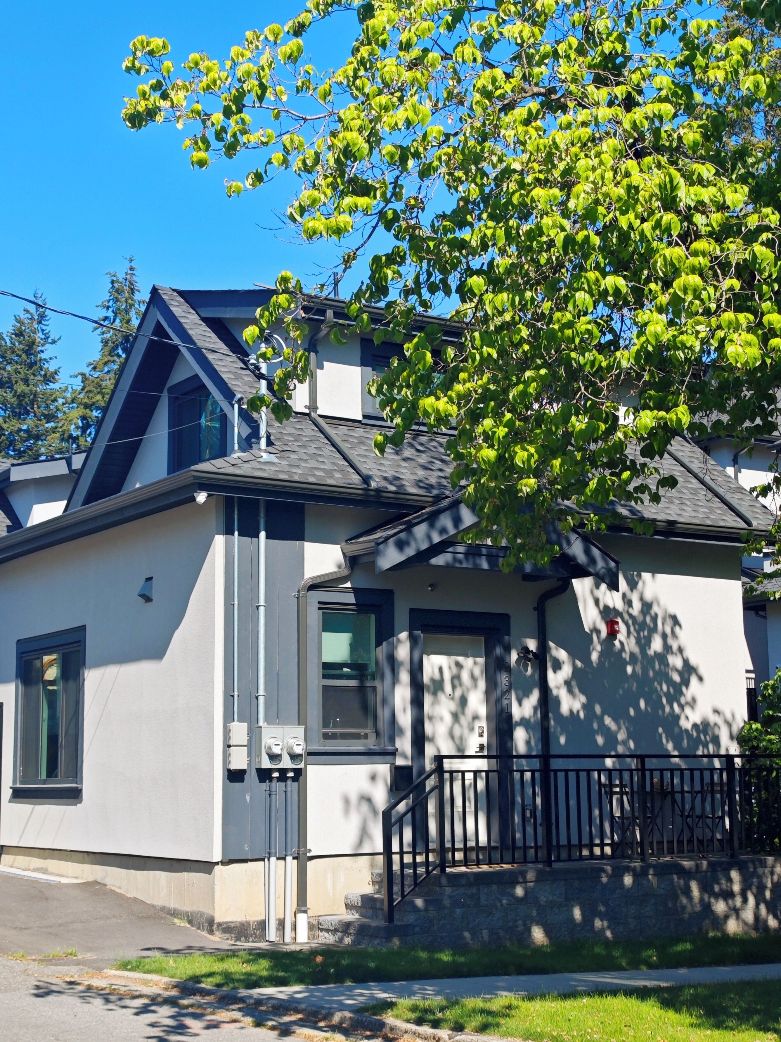 A modern two-story house with a sloped roof, a visible chimney, and a front porch with a black railing.