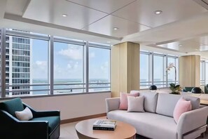 Eine moderne Hotelhalle mit großen Fenstern, einer Couch, einem Sessel und einem Couchtisch.