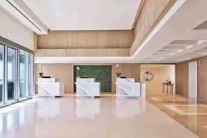 Eine moderne Lobby mit drei Rezeptionstheken, einer grünen Wand und einem polierten Boden.