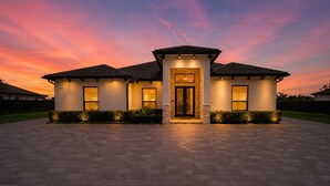 A modern house with a paved driveway, a central entrance, and two side entrances. - Luxury Miami 5BR Retreat W/Pool,Jacuzzi & Outdoor Kitchen . (Miami)