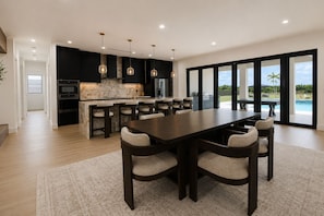 Una cocina moderna con una isla grande, taburetes de bar e iluminación colgante.