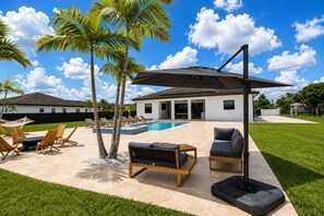 Ein Poolbereich mit Liegestühlen, einem Tisch und einem großen Sonnenschirm.