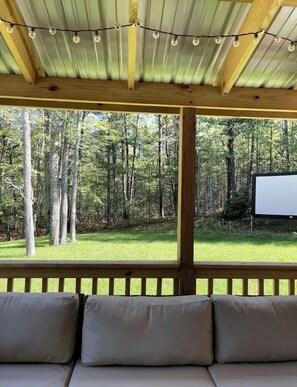 A covered outdoor seating area with a view of a forest. - Adorable 2-bedroom house with AC in peaceful Roscommon (Roscommon)
