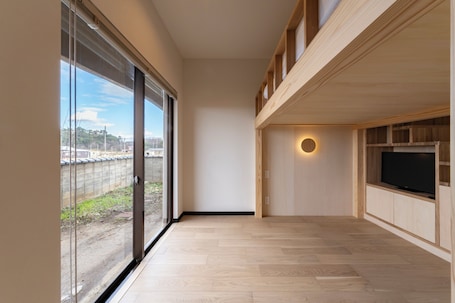 A modern interior with large windows, a flat-screen TV, and a wooden ceiling.. kitamae-base.com