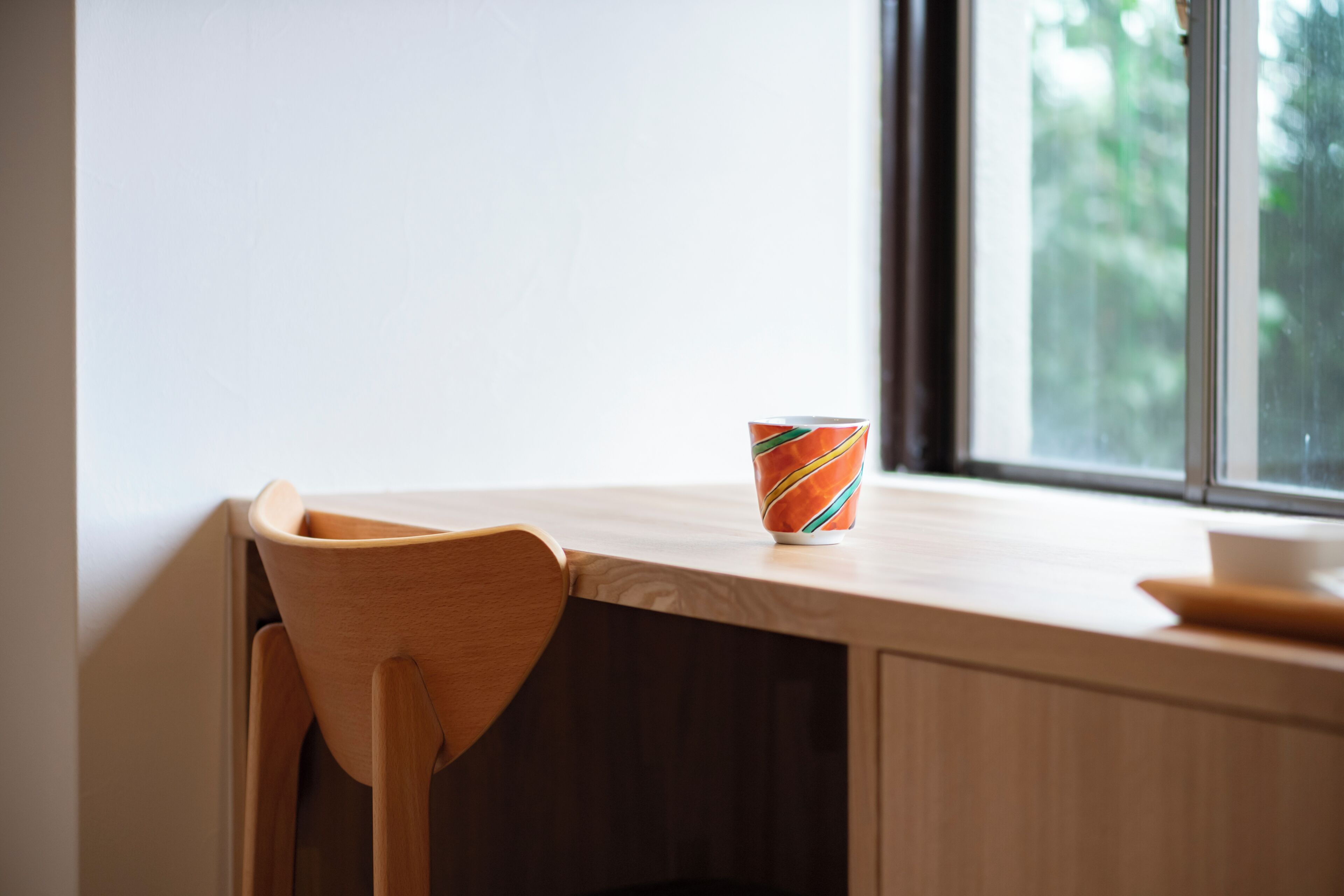Una silla de madera y una mesa con una taza de colores.
