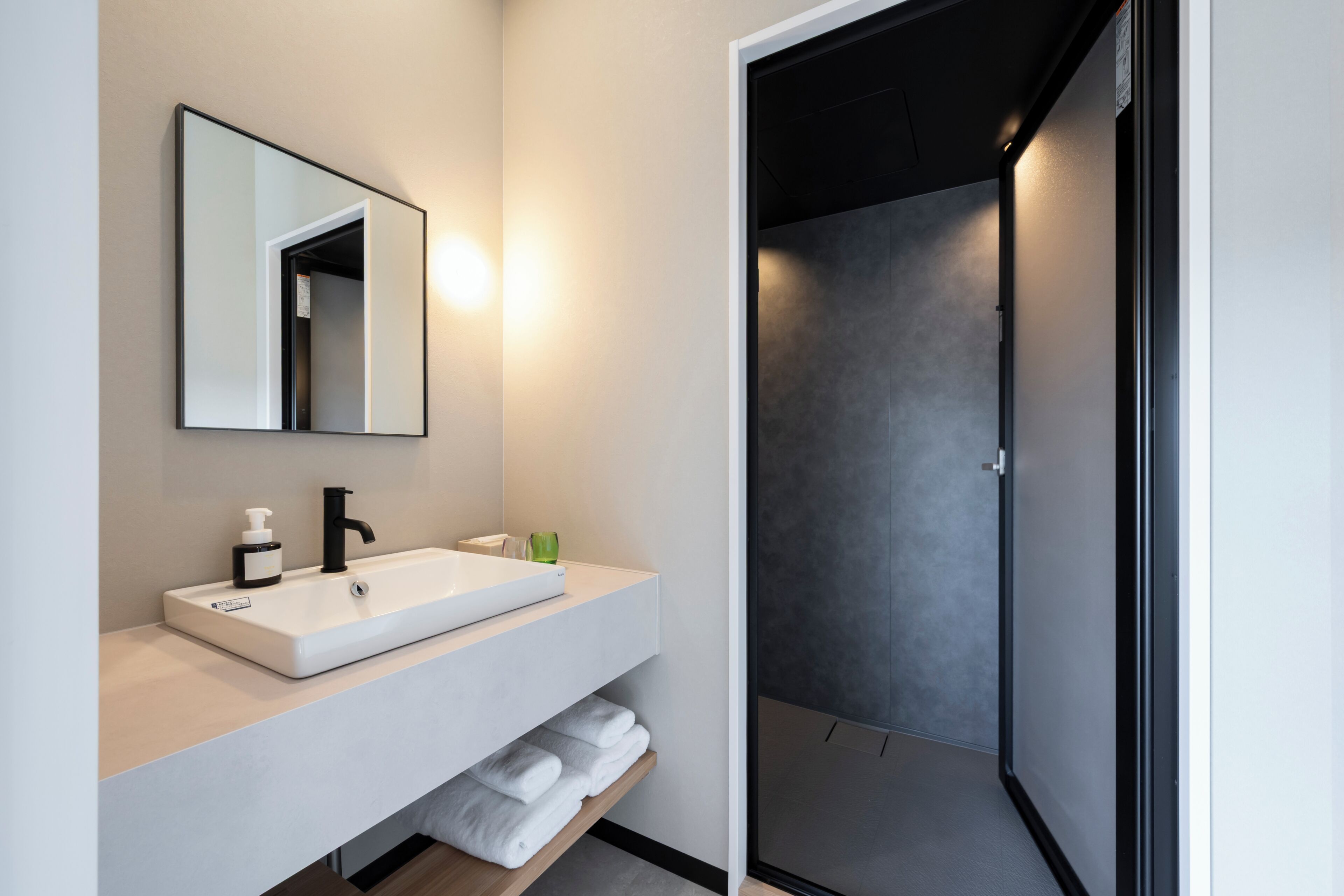 Un baño moderno con un lavamanos blanco, un espejo y un perchero para toallas.